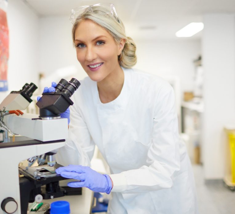 Dr Megan Rossi in a lab looking through a microscope