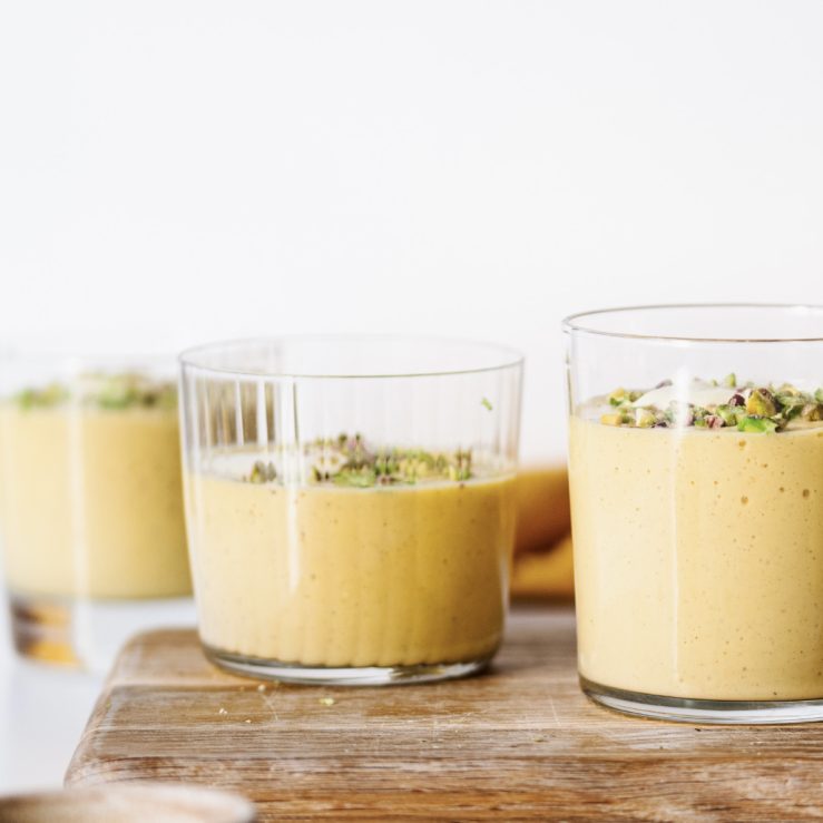 Three pots of gut-loving mango pudding, topped with chopped pistachios