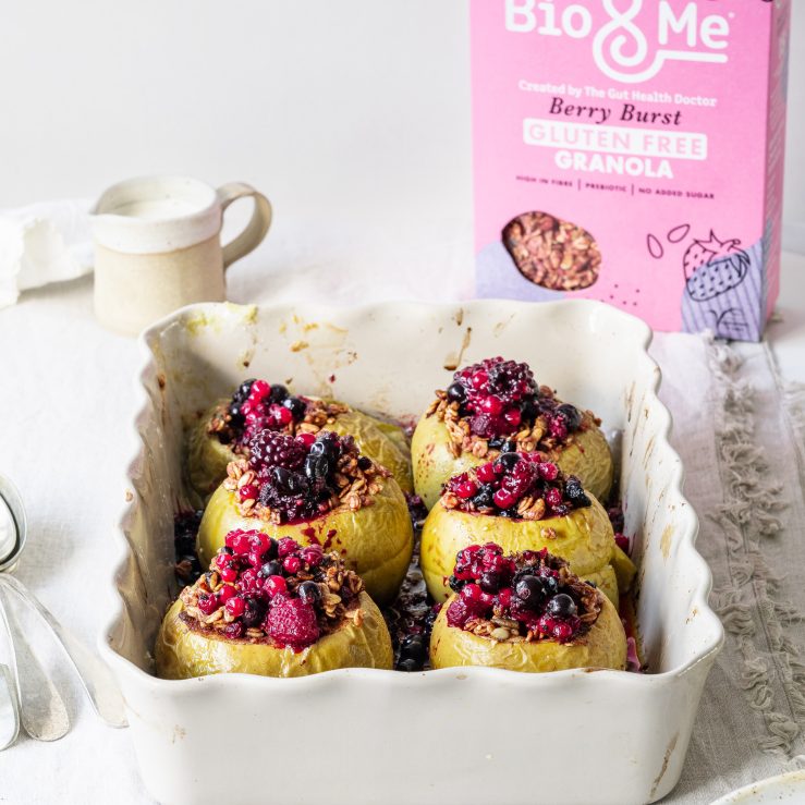 A white oven dish containing 6 super berry stuffed and baked apples