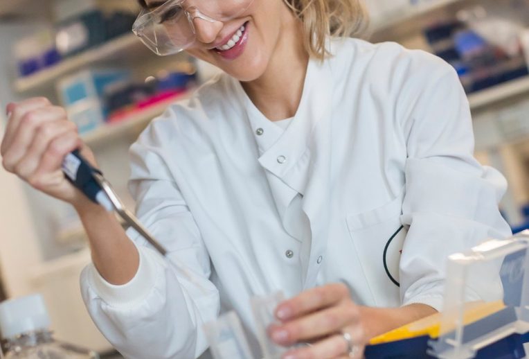 Dr Megan Rossi in a lab looking through a microscope