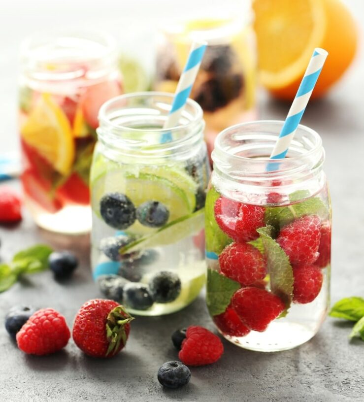 Photo of two mason jars with water and cucumber, blueberries, strawberries and mint included