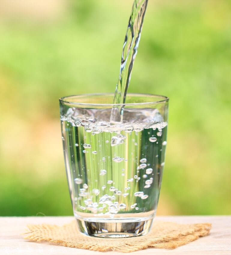 Photo of water being poured into a glass on a table