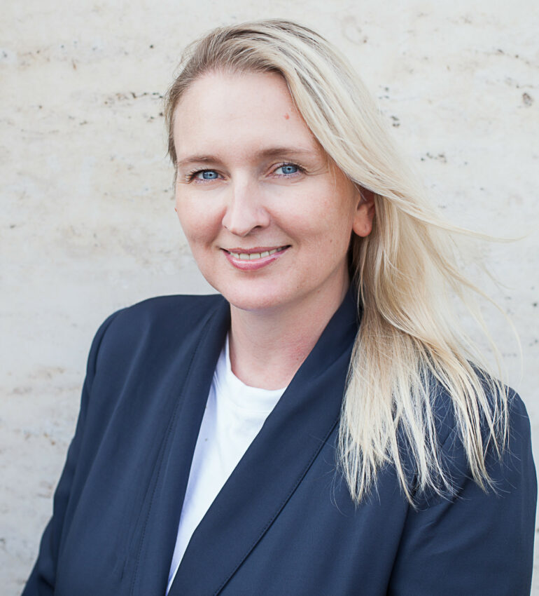 Image of Anna smiling, she has blonde hair and is wearing a blazer