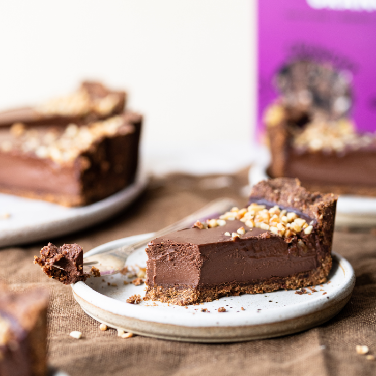 Photo of a slice of Bio&Me hazelnut & chocolate tart with Bio&Me packaging in the background and a fork next to tart