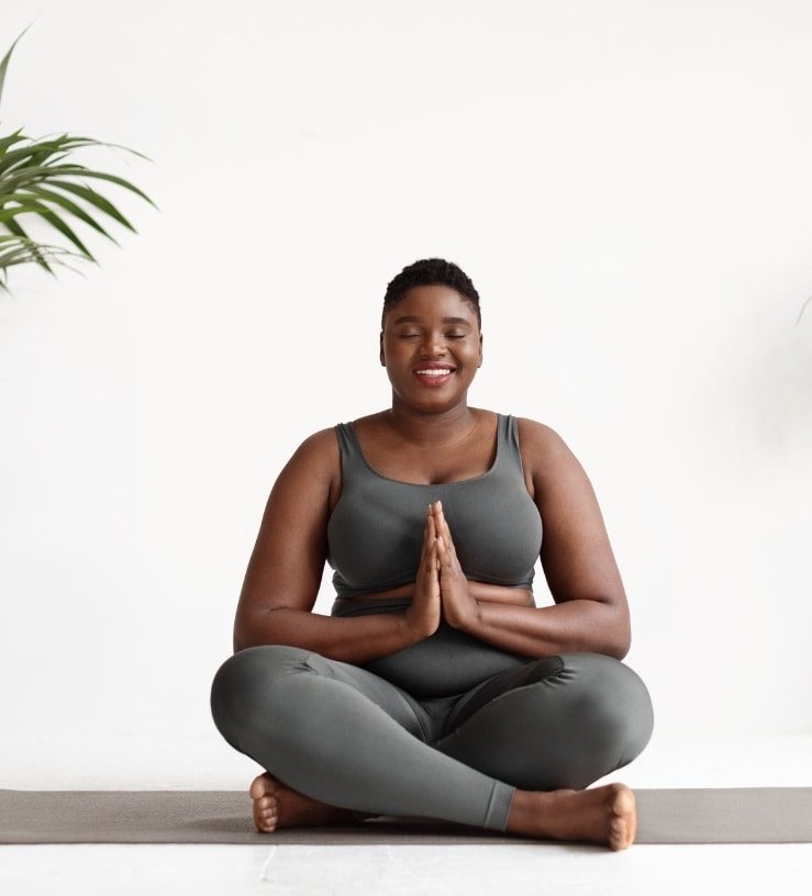 A woman sitting down, cross legged with her workout gear on