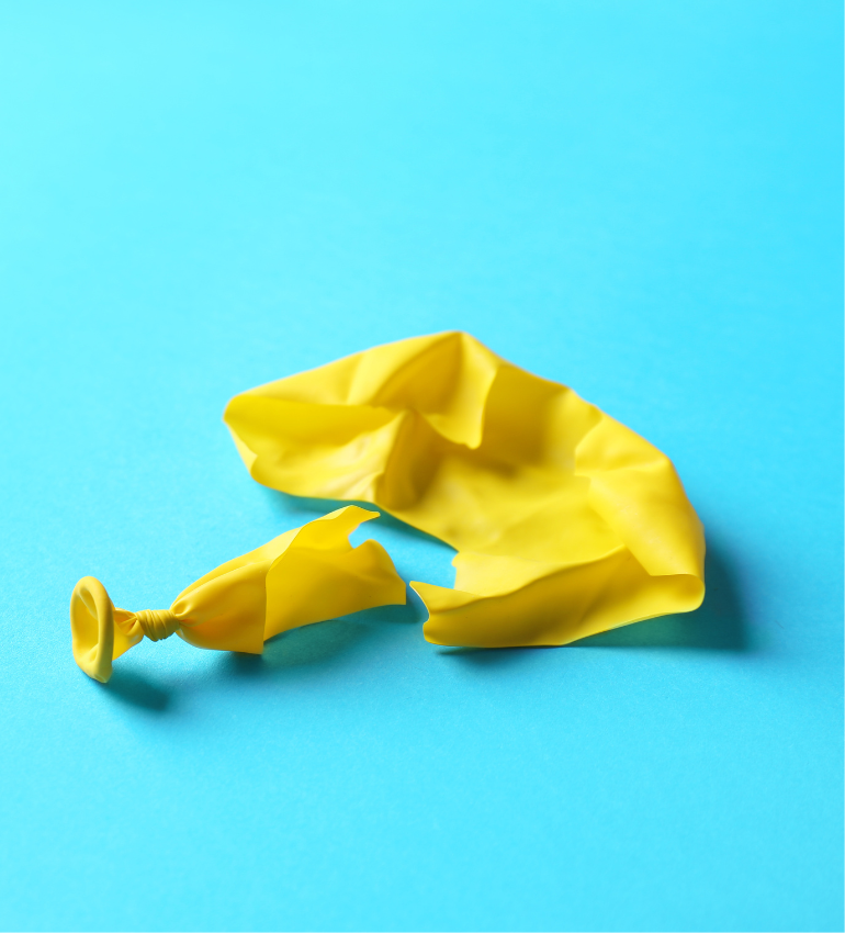 Photo of a popped yellow balloon on a blue background