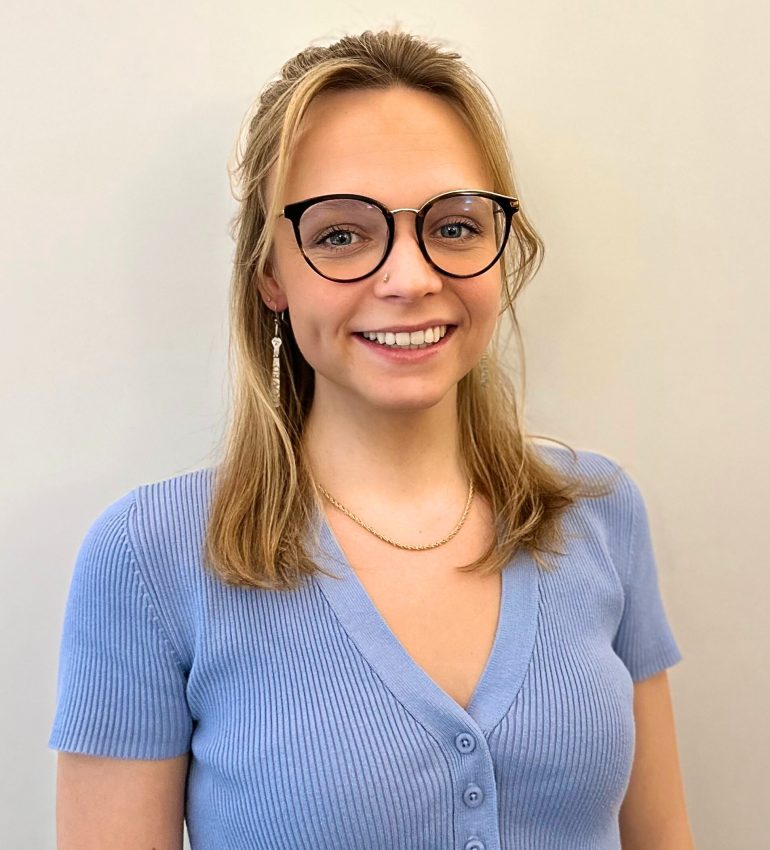 An image of Gabrielle Morse smiling, a blonde woman wearing glasses