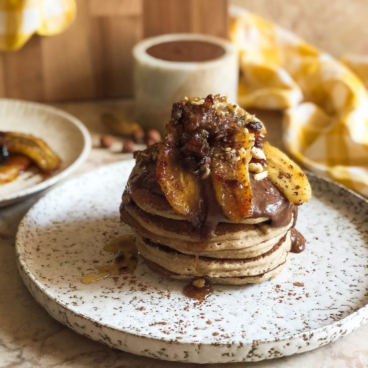 A stack of pancakes with homemade nutella and caramelised bananas on top