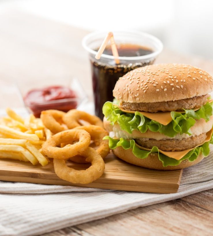 A photo of a cheeseburger with fries and onion rings