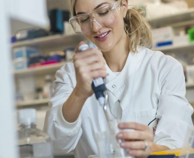 Dr Megan Rossi in a lab looking through a microscope